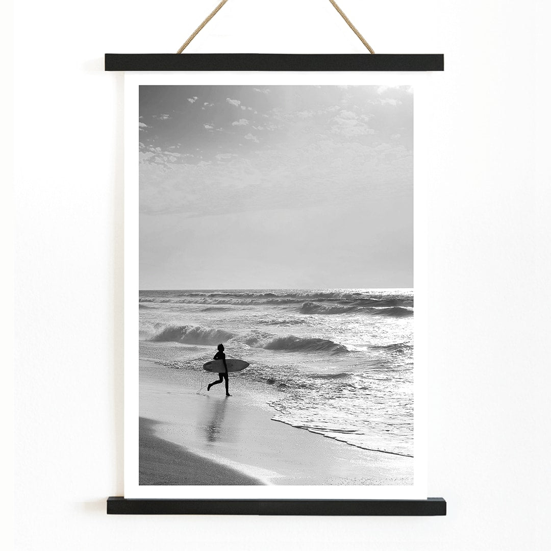 Black and white poster of a surfer with a board entering the ocean titled Surfer in Portugal by artist Black, with wooden magnetic frame on white background