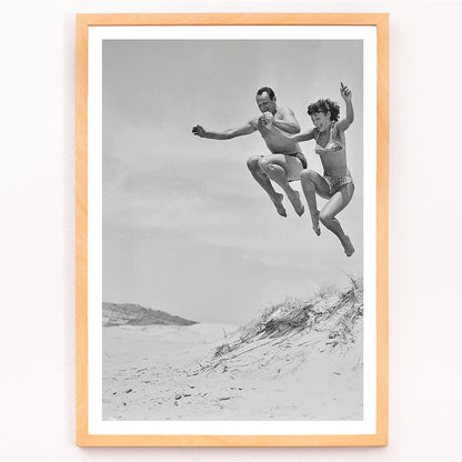 Two Tivoli Stars performing an acrobatic jump on a sandy beach in swimsuits Acrobatics at the Beach poster, framed and displayed in modern living room decor