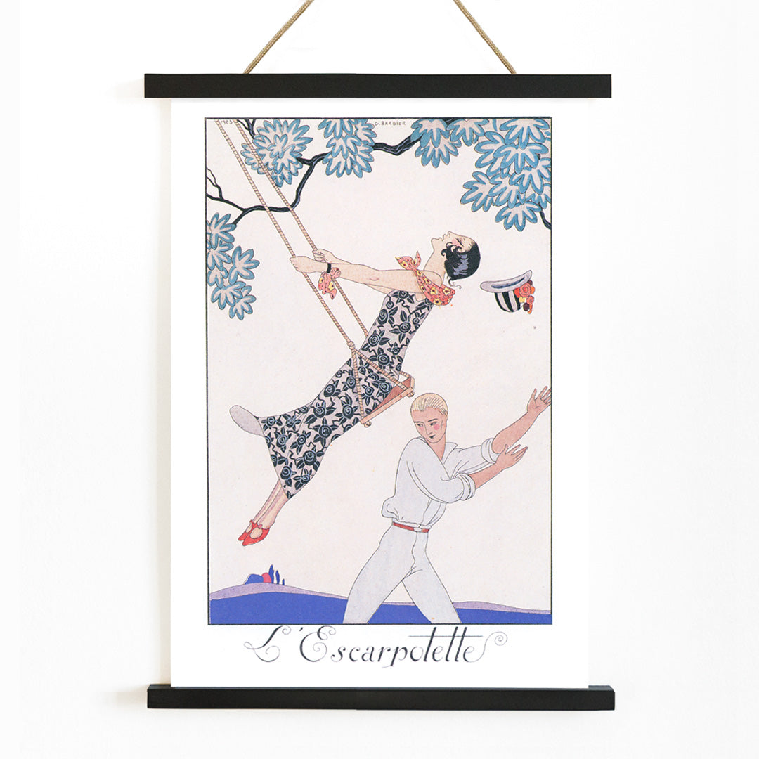 Art Deco poster of a woman on a swing with a man beneath under a tree from LEscarpotette by George Barbier, with wooden magnetic frame on white background