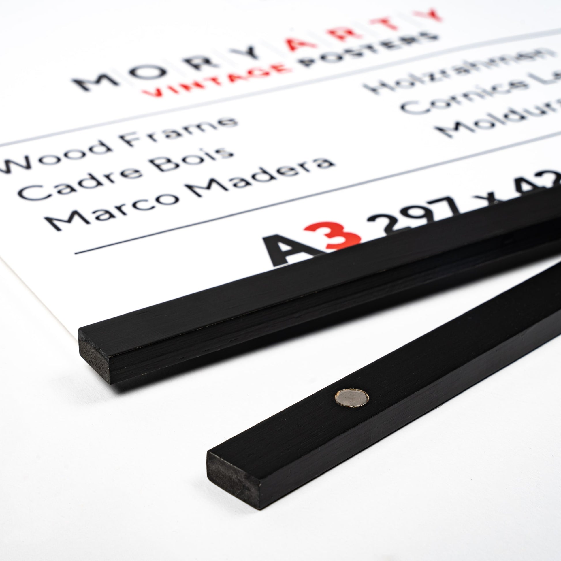 Black Pine magnetic wood frame with two sleek wooden bars and a simple rope for hanging, displaying a poster on a wall in a modern, elegant setting, back corner closeup picture