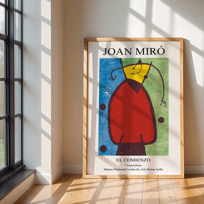 Exhibition poster of El Comienzo by Joan Miro with colorful abstract shapes and vibrant colors in a framed display, framed and displayed in modern living room decor