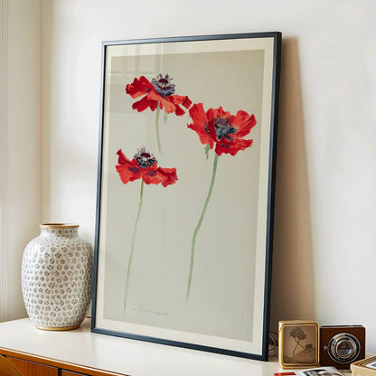 Three Studies of Poppies by Sophia Crownfield poster featuring vibrant red poppies on delicate stems and a light background artwork, framed and displayed in modern living room decor