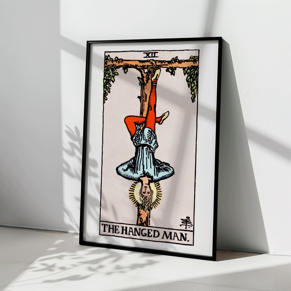 Hanged Man Tarot Card by Rider Waite, figure hanging upside down from wooden structure, mystical poster art, framed and displayed in modern living room decor