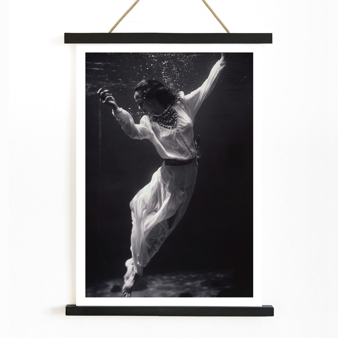 Black and white artwork of a fashion model floating underwater in dolphin tank Marineland Florida by Toni Frissell, with wooden magnetic frame on white background